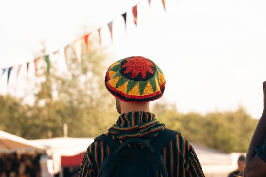 Festivalbezoeker met rasta-muts, van achteren, met vlaggetjes op de achtergrond
