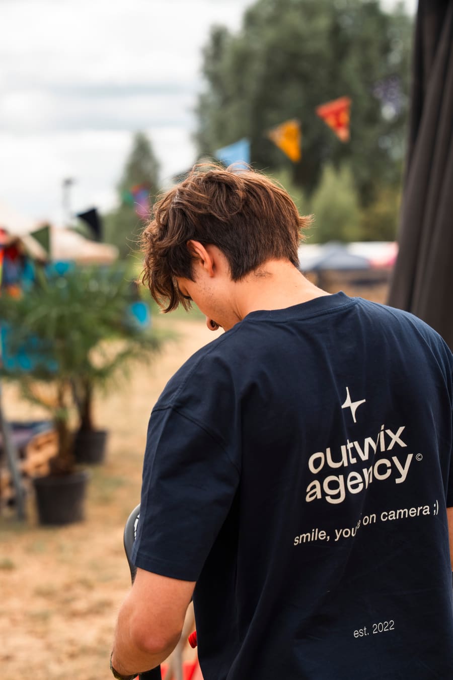 Persoon in Outwix Agency-shirt van achteren, wandelend over het festivalterrein