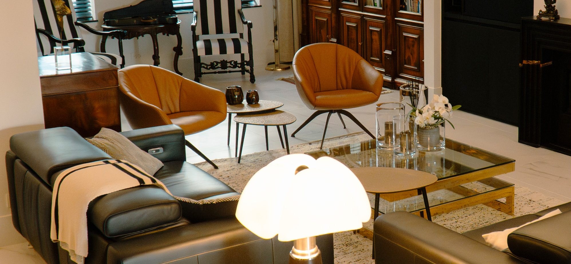 Woonkamer met cognac leren stoelen, gestreepte fauteuils en een lederen zetel