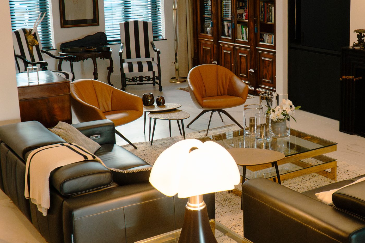 Woonkamer met lederen zetels, cognac stoelen en een glazen salontafel