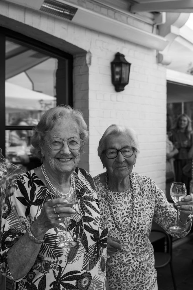 Twee lachende dames aan tafel, in zwart-wit