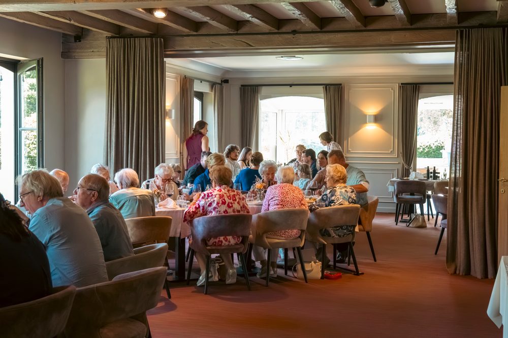 Volle feestzaal met gasten aan gedekte tafels