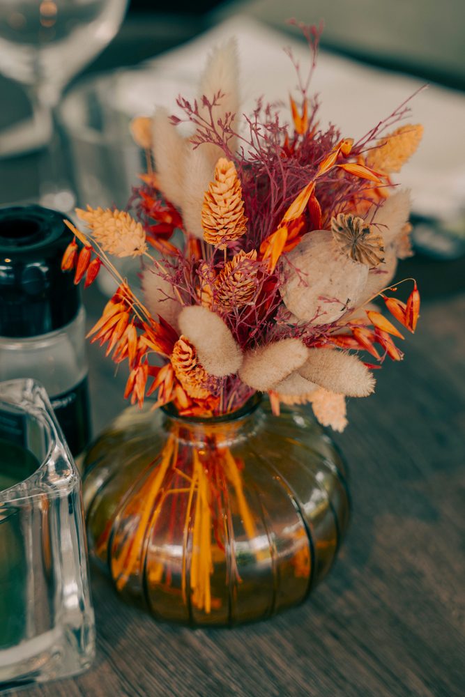 Vaas met oranje droogbloemen op tafel