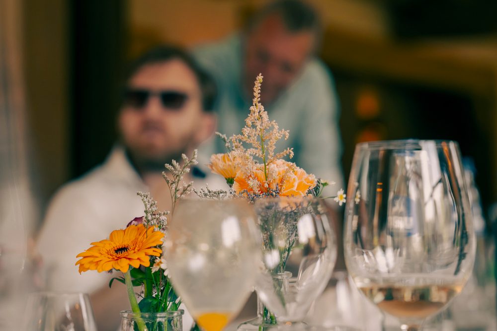 Gast met zonnebril achter een boeket bloemen
