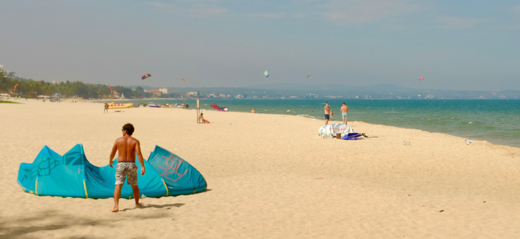 Strand van Knokke met een kitesurfer die zijn turquoise vlieger klaarlegt